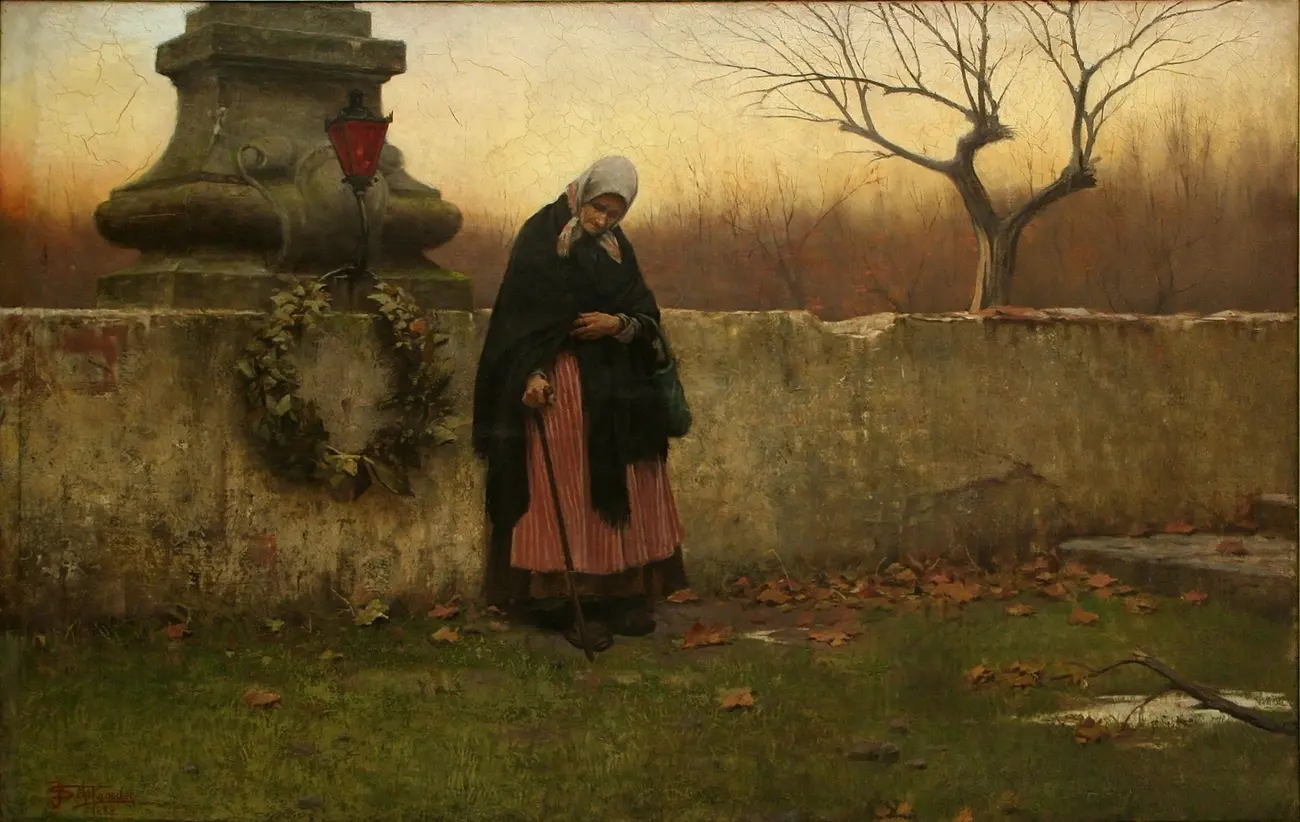 An elderly woman walks beside a cemetery wall on All Souls’ Day
